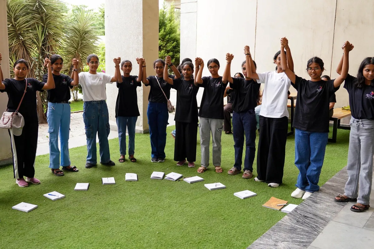 Adira students on a lawn, hands raised